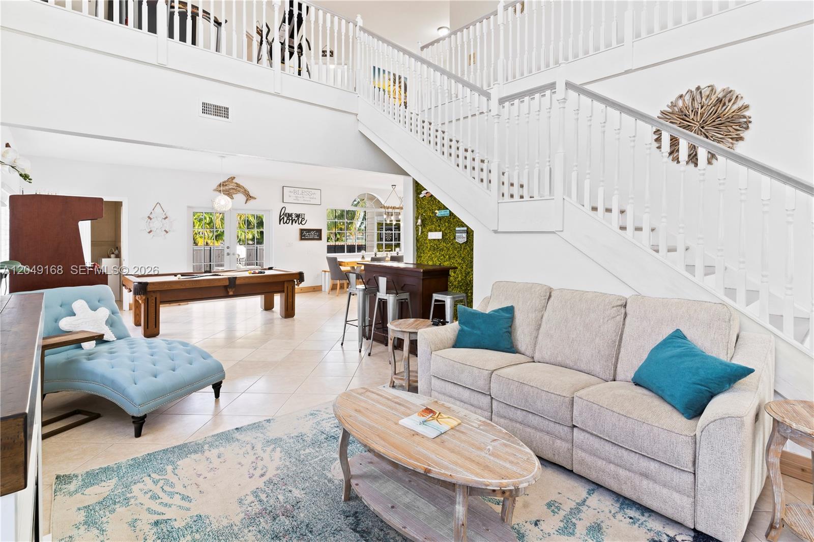 A spacious living room features a staircase, pool table, bar area, and neutral furniture — 901 Dove Ave, Miami Springs FL 33166, MIAMI SPRINGS, FL
