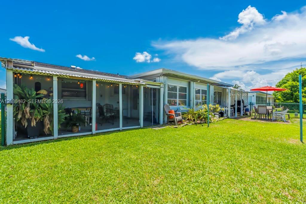 The exterior of a house features a screened-in porch, a grassy lawn, and a patio — 4923 NW 55th Ct, Tamarac FL 33319, TAMARAC, FL