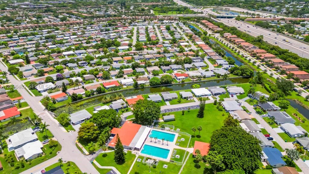 An aerial view shows a residential neighborhood with a community pool and a canal — 4923 NW 55th Ct, Tamarac FL 33319, TAMARAC, FL