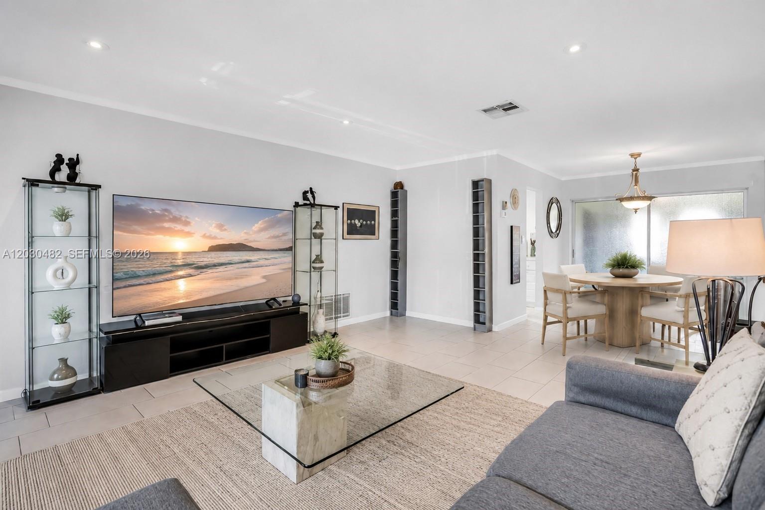 A living room features a large television, glass display cabinets, and a dining area nearby — 4923 NW 55th Ct, Tamarac FL 33319, TAMARAC, FL