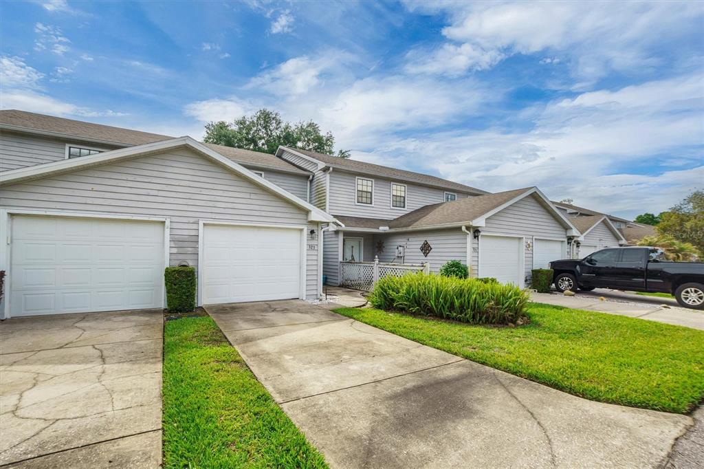 A view of the exterior of a multi-unit residential building with attached garages and driveways — 323 ORANGE BLOSSOM DRIVE UNIT 323, WINTER HAVEN, FL