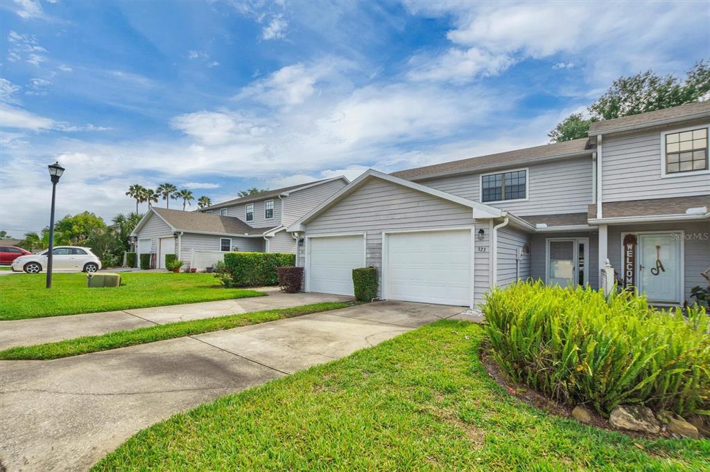 A two-story townhouse with gray siding, a two-car garage, and a front lawn — 323 ORANGE BLOSSOM DRIVE UNIT 323, WINTER HAVEN, FL