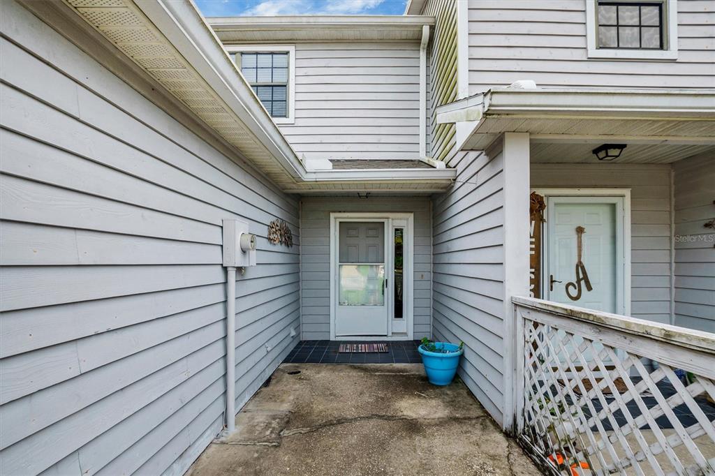 A concrete entryway leads to a front door with a storm door and a porch — 323 ORANGE BLOSSOM DRIVE UNIT 323, WINTER HAVEN, FL