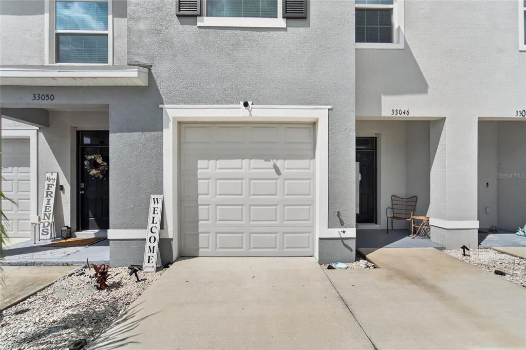 The exterior view shows a two-story townhouse with a garage, front entrance, and concrete driveway. n — 33046 MAJOR OAK DRIVE, WESLEY CHAPEL, FL