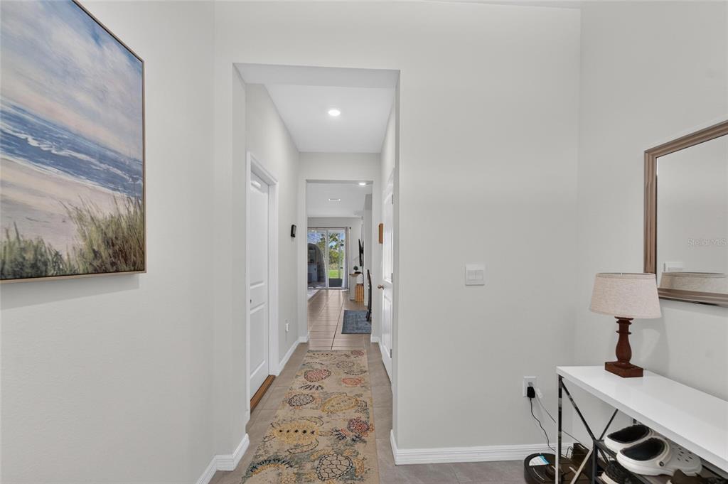 A bright hallway features light tile flooring, a patterned runner rug, and white walls — 33046 MAJOR OAK DRIVE, WESLEY CHAPEL, FL