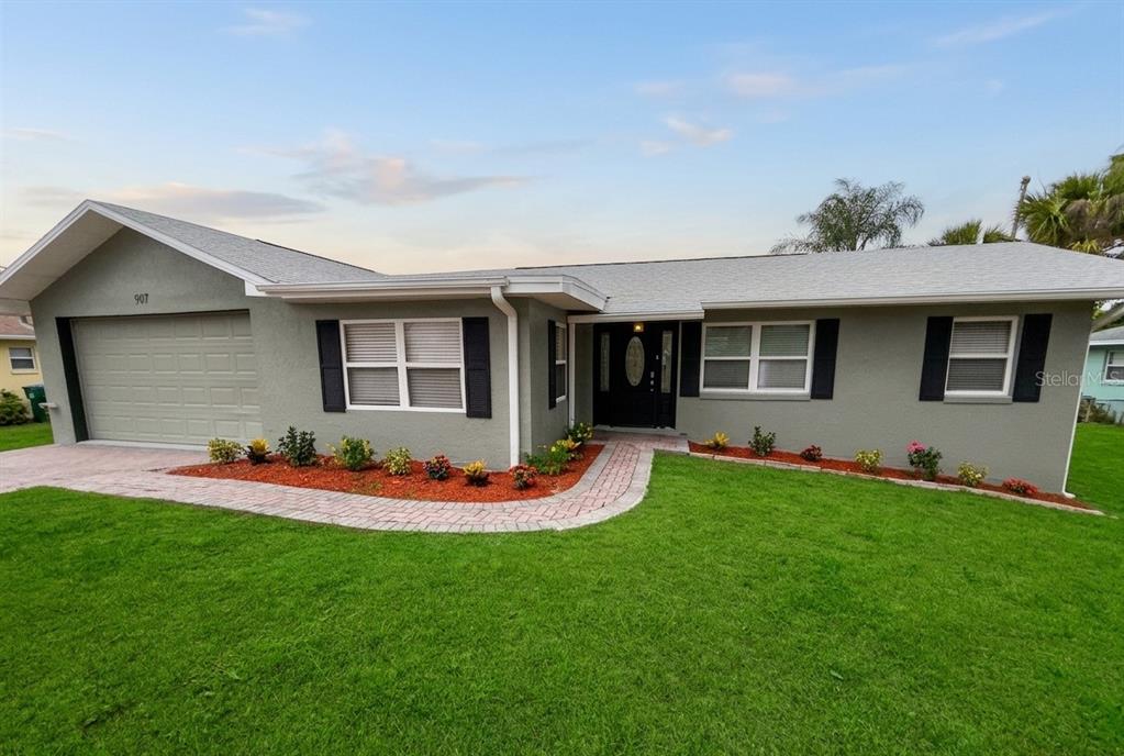 A single-story house with a gray stucco exterior, a garage, and a brick walkway — 907 VALENTINA DRIVE, DUNDEE, FL