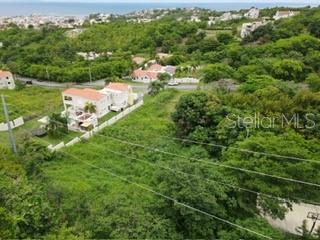 An aerial view shows a vacant, grassy lot adjacent to a two-story house and trees — 1 HARBOURLIGHTS ESTATES EXTENSION UNIT 52, HUMACAO, PR