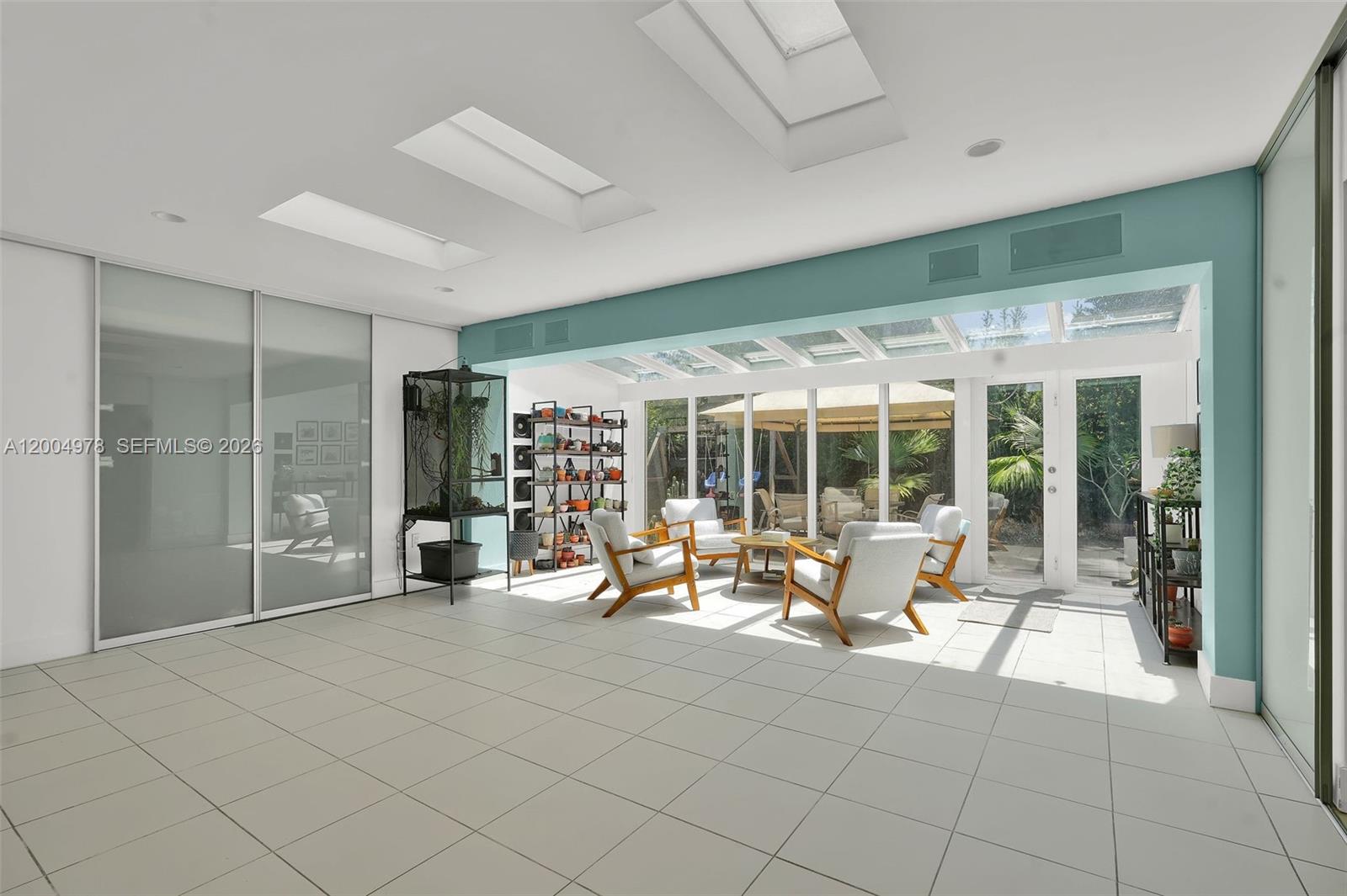 A sunroom with white tile floors, a glass ceiling, and sliding doors leading to a patio — 15540 SW 152nd Ter, Miami FL 33187, MIAMI, FL