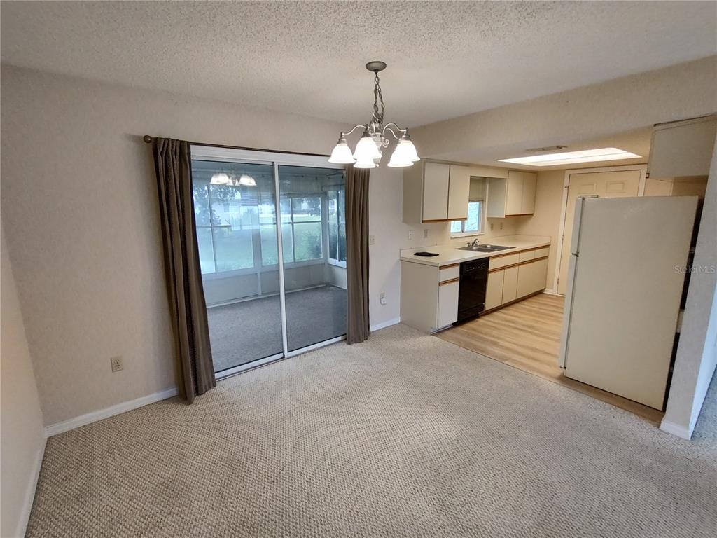 A dining area with carpeted flooring, a sliding glass door, and an adjacent kitchen — 6345 SW 115TH STREET ROAD, OCALA, FL