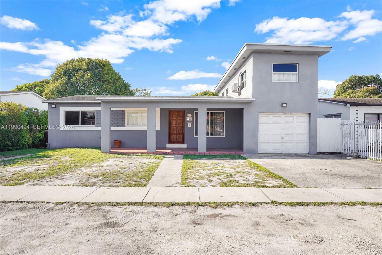 A gray, two-story house features a covered front porch, a garage, and a front lawn — 760 E 55th St, Hialeah FL 33013, HIALEAH, FL
