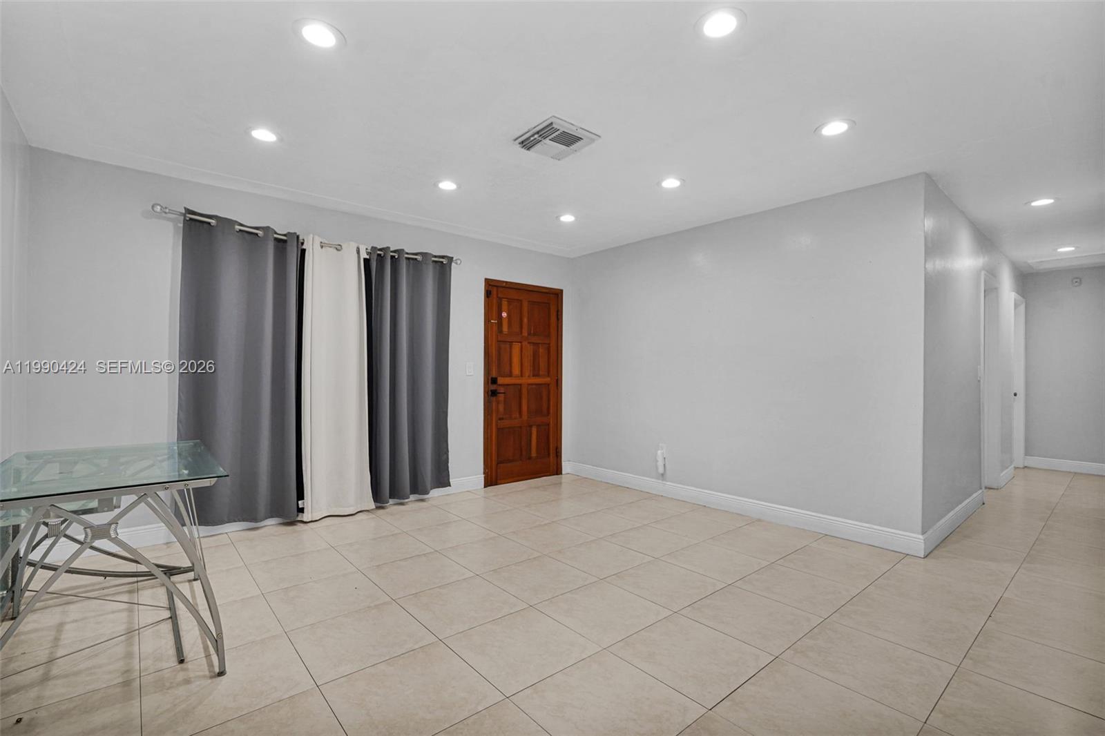 A bright, tiled living area features a wooden front door and recessed ceiling lighting — 760 E 55th St, Hialeah FL 33013, HIALEAH, FL
