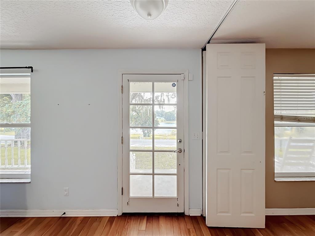 A room with light blue walls, wood flooring, a glass-paneled door, and two windows — 540 DREW AVENUE, CLERMONT, FL