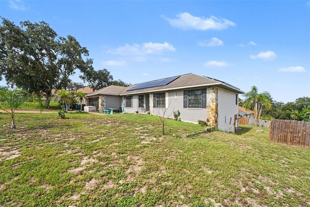A single-story house with solar panels on the roof and stone accents on the exterior — 818 CAMBRIDGE WAY, LAKE WALES, FL