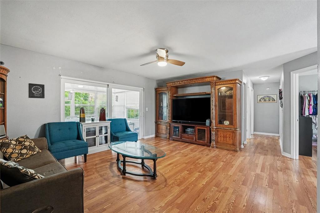 A living room features wood flooring, a large entertainment center, and two blue armchairs — 818 CAMBRIDGE WAY, LAKE WALES, FL