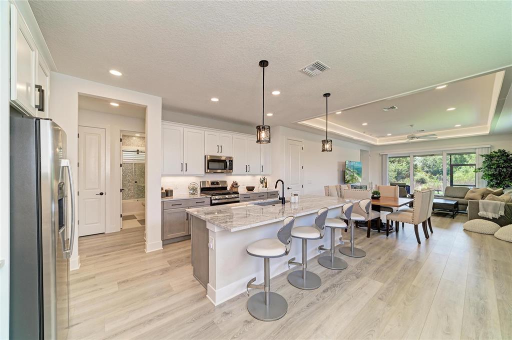 A modern kitchen features white upper cabinets, gray lower cabinets, a marble island, and barstools — 1047 WATERLINE COURT, SARASOTA, FL