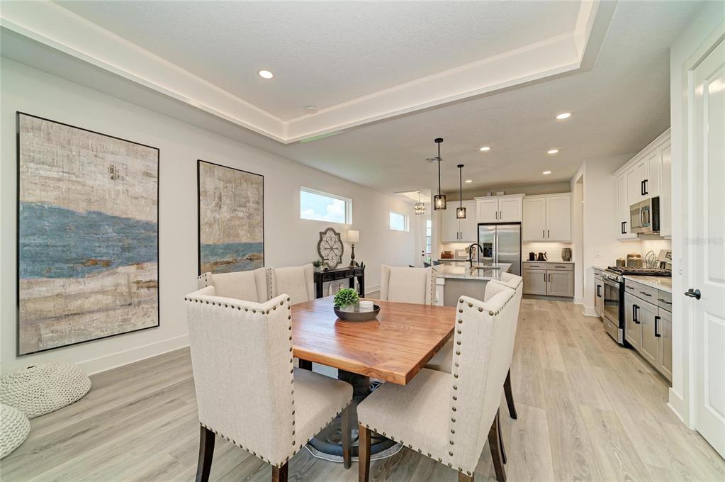 A dining area with a wooden table and upholstered chairs opens into a modern kitchen — 1047 WATERLINE COURT, SARASOTA, FL