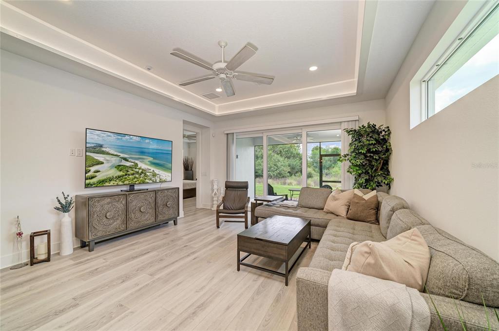 A living room features a sectional sofa, a television on a console, and sliding glass doors — 1047 WATERLINE COURT, SARASOTA, FL