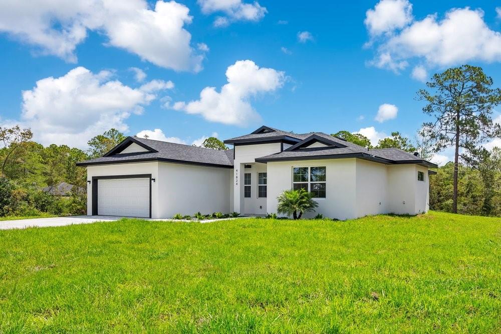 A modern white single-story house with a dark roof and a two-car garage — 41824 ASPEN STREET, EUSTIS, FL