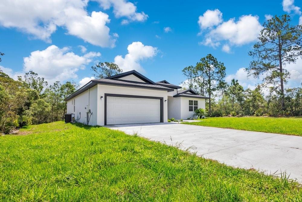 A white single-story house with a two-car garage sits on a grassy lot — 41824 ASPEN STREET, EUSTIS, FL
