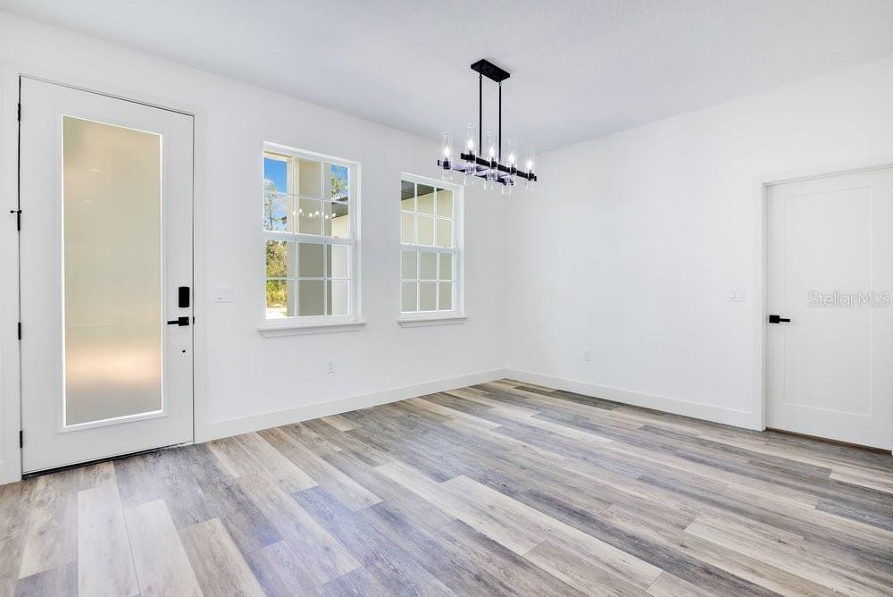A bright room with white walls, wood-look flooring, two windows, and a modern chandelier — 41824 ASPEN STREET, EUSTIS, FL