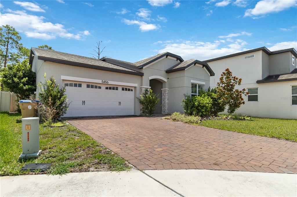 A single-story house with a paved driveway, a two-car garage, and a covered entryway — 5456 CARRARA COURT, ST CLOUD, FL