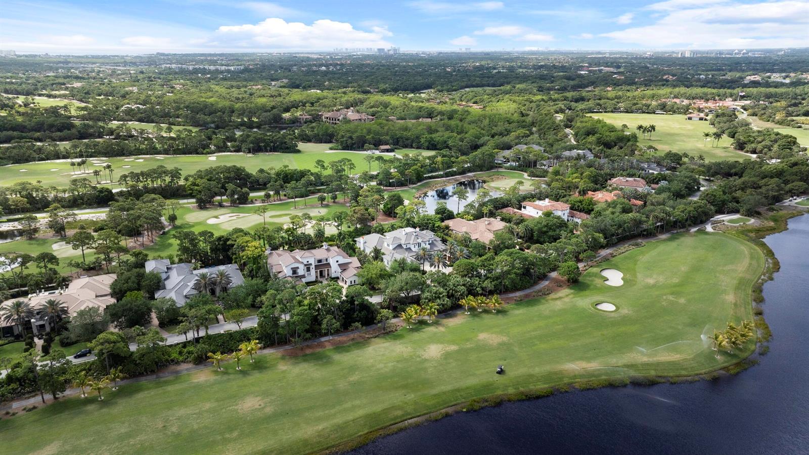 An aerial view shows luxury homes situated along a golf course and a large lake — 131 W Bears Club Drive, Jupiter FL 33477, JUPITER, FL