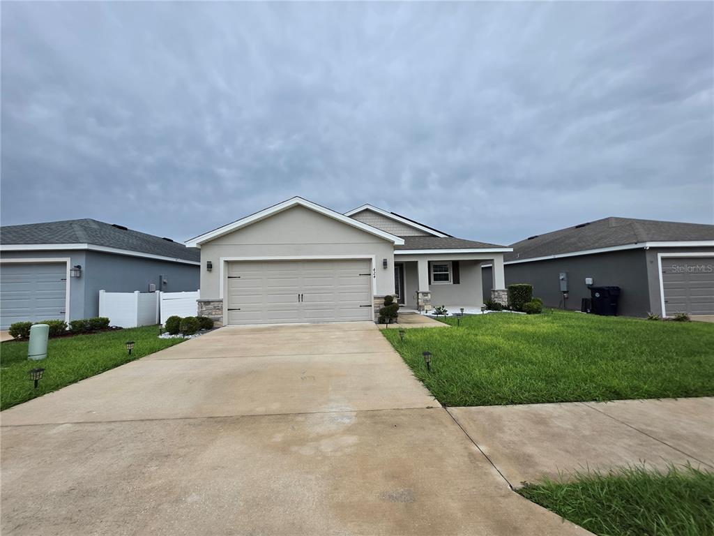 A single-story suburban house with a two-car garage and a concrete driveway — 424 CAPRI WAY, AUBURNDALE, FL