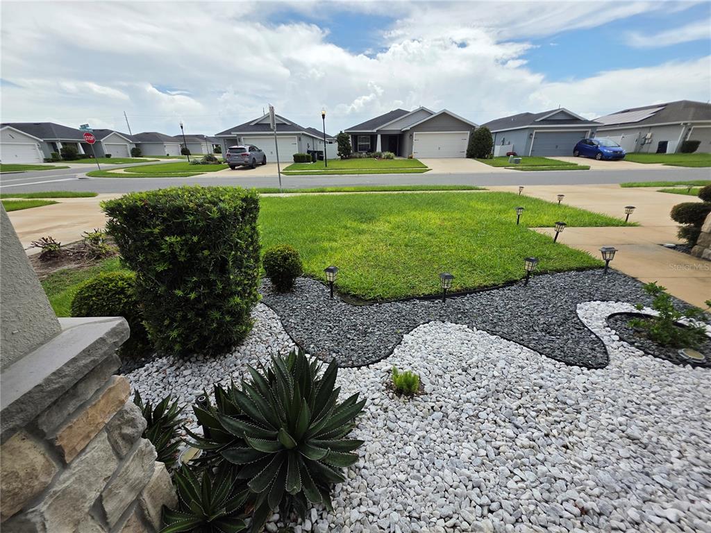 A front yard features a landscaped garden bed with white and gray rocks and succulents — 424 CAPRI WAY, AUBURNDALE, FL