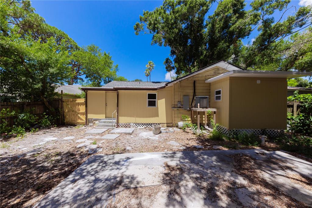 The exterior of a yellow house features a concrete patio and a fenced backyard — 2240 10TH STREET S, ST PETERSBURG, FL