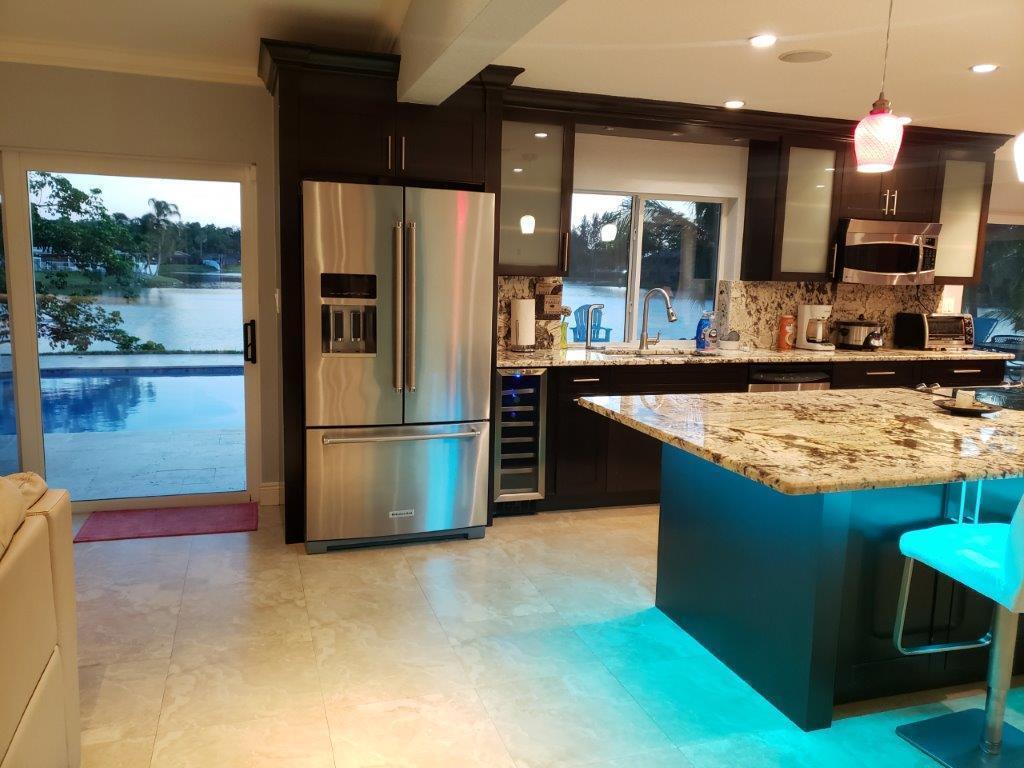 A kitchen with dark cabinets, granite countertops, a stainless steel refrigerator, and a pool view — 801 NW 49th Way, Coconut Creek FL 33063, COCONUT CREEK, FL