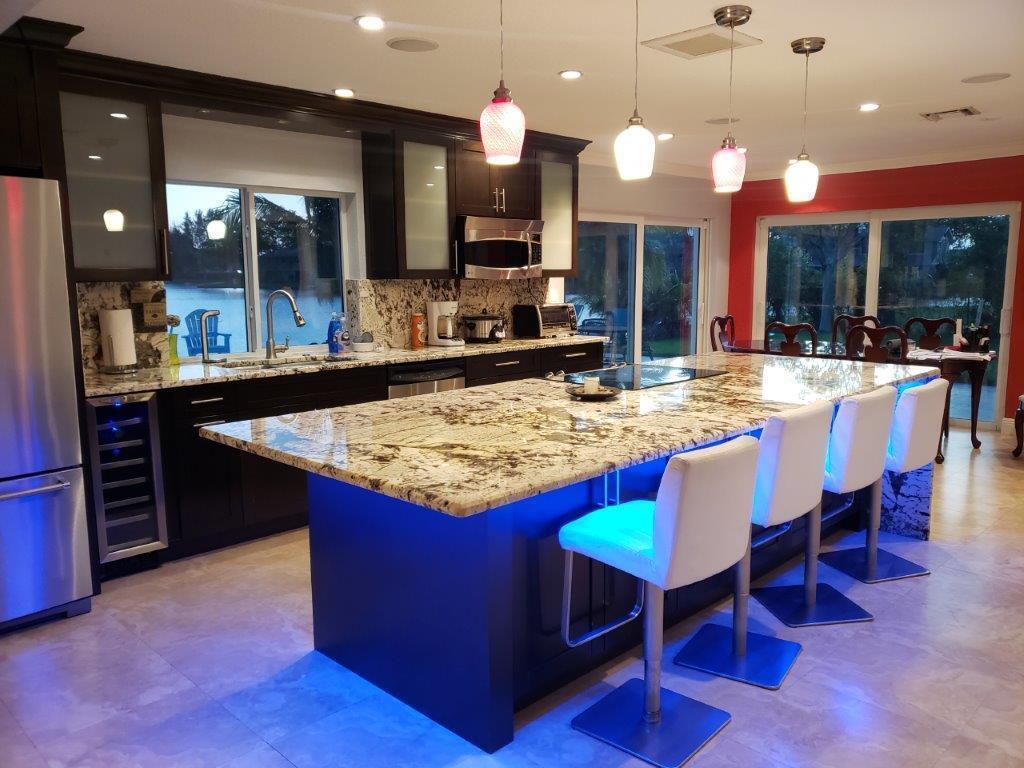 A modern kitchen features dark cabinetry, granite countertops, a large island, and blue under-cabinet lighting — 801 NW 49th Way, Coconut Creek FL 33063, COCONUT CREEK, FL