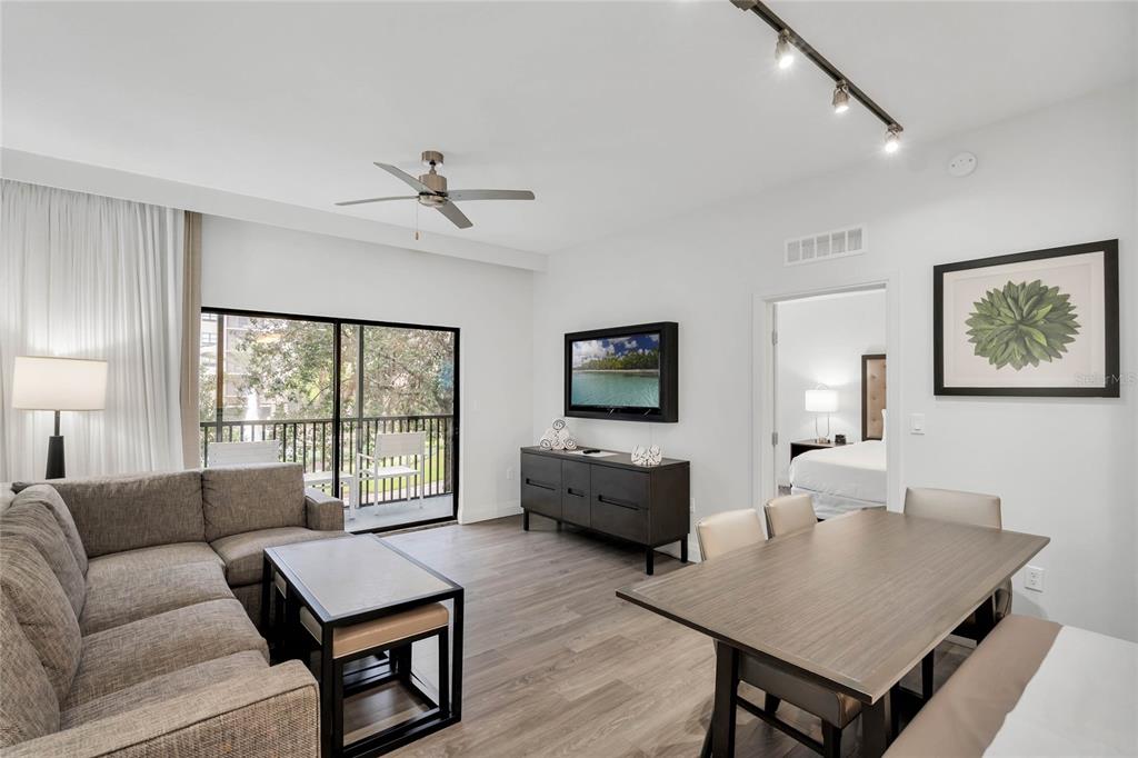 A living and dining area with gray wood-look flooring, a sectional sofa, and a balcony — 14501 GROVE RESORT AVENUE UNIT 3205, WINTER GARDEN, FL