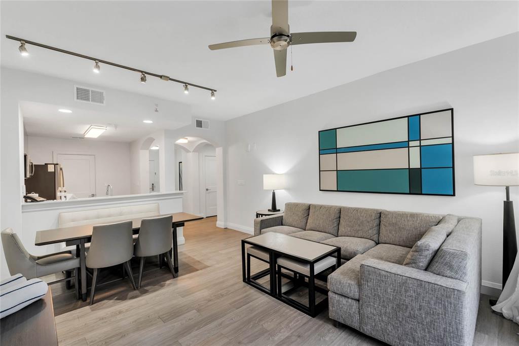 A living and dining area features a gray sectional sofa, dining table, and track lighting — 14501 GROVE RESORT AVENUE UNIT 3205, WINTER GARDEN, FL