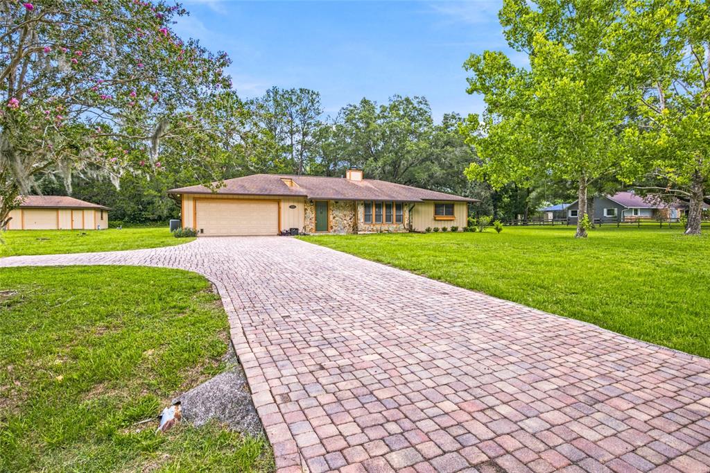 A single-story house with a stone facade and a brick paver driveway sits on grass — 5143 SE 17TH STREET, OCALA, FL