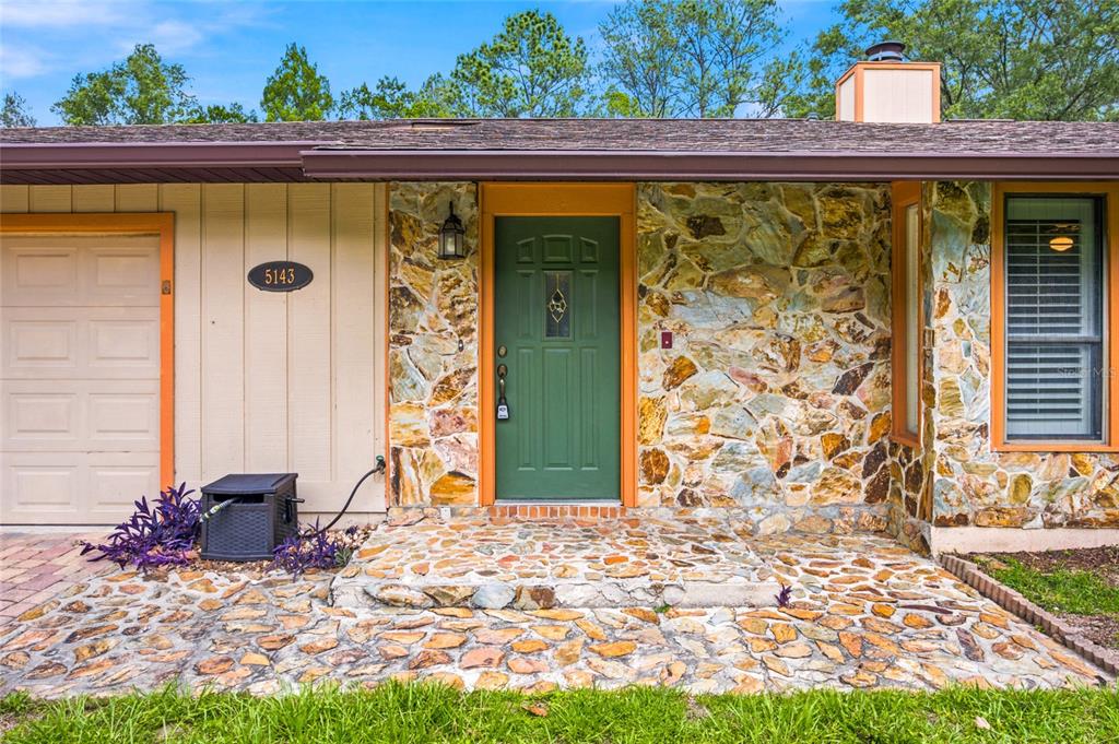 The exterior of a house features a green front door, stone siding, and a garage — 5143 SE 17TH STREET, OCALA, FL