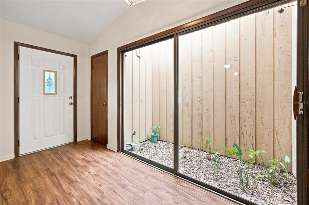 An entryway with wood-look flooring features a white front door and a sliding glass door — 5143 SE 17TH STREET, OCALA, FL