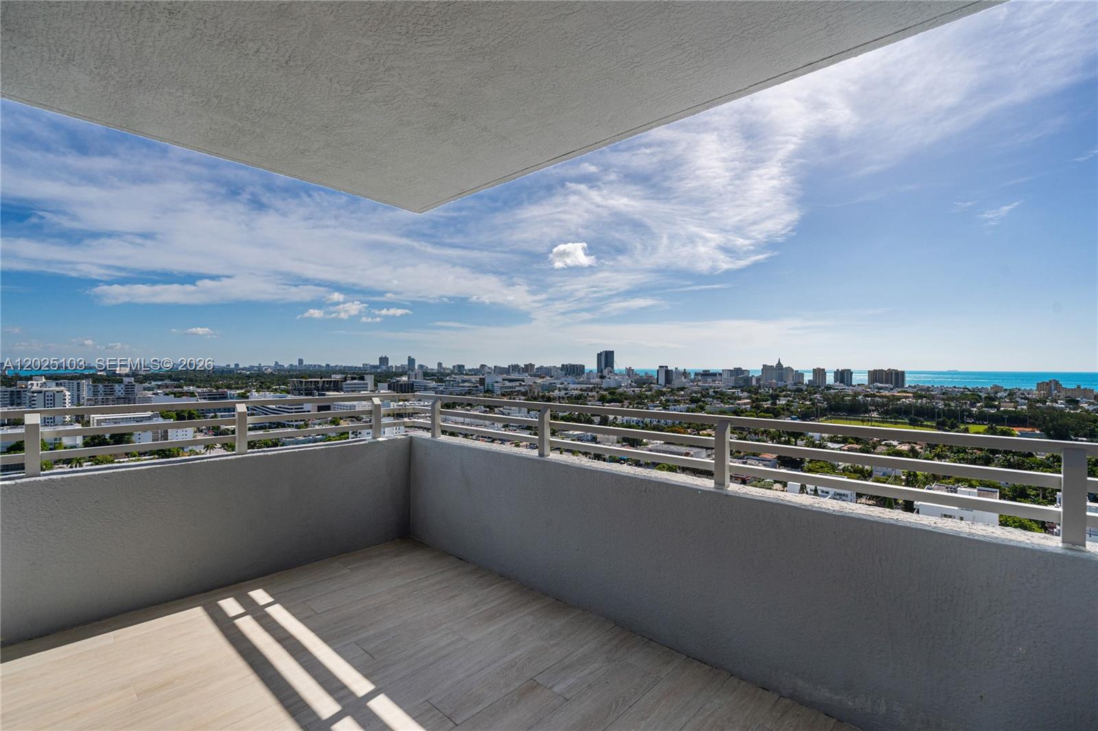 A balcony with light-colored tile flooring overlooks a city skyline and the ocean — 1330 West Ave # 2107, Miami Beach FL 33139, MIAMI BEACH, FL