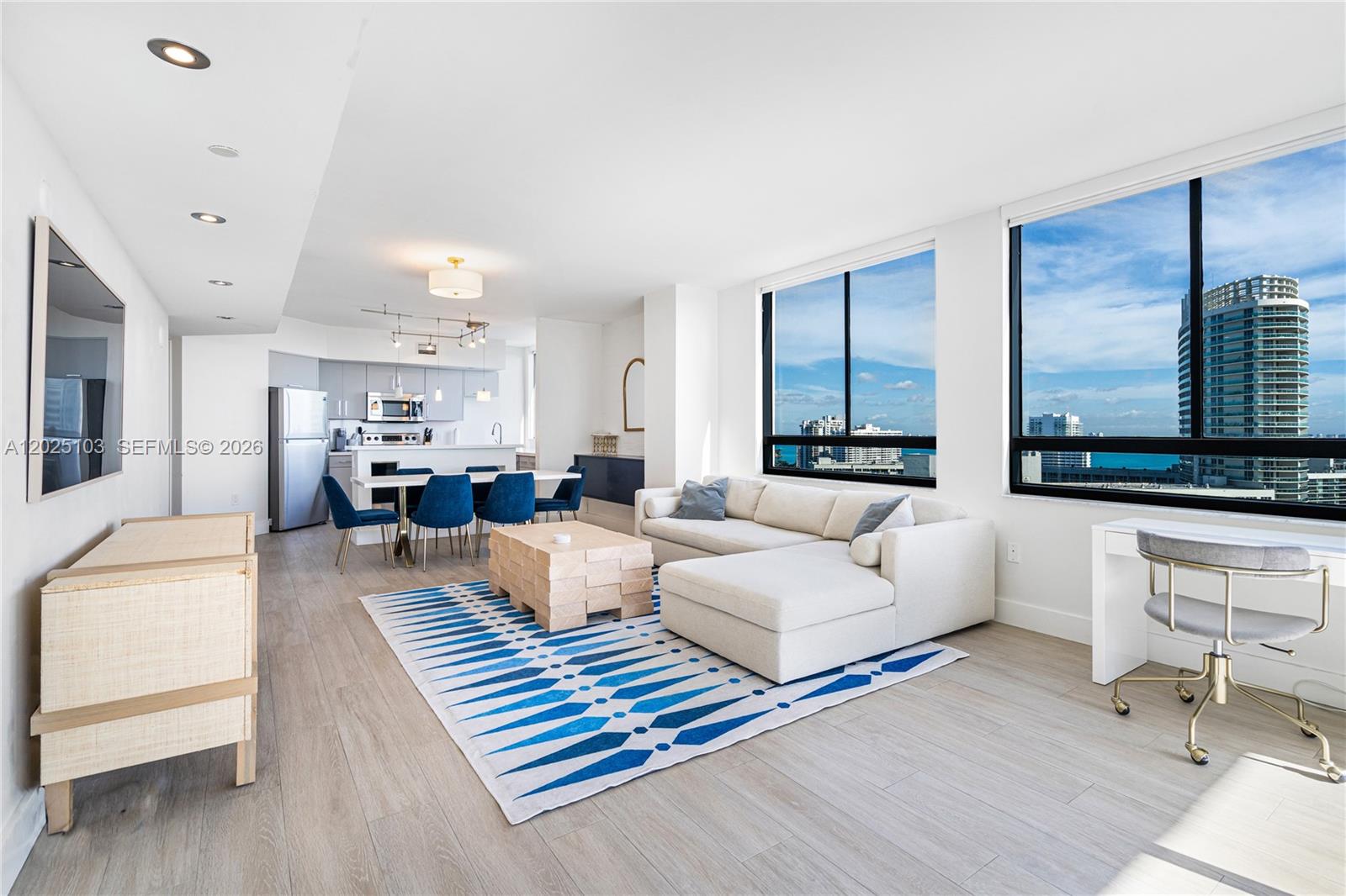 A modern open-concept living and dining area features a white sectional, blue chairs, and ocean views — 1330 West Ave # 2107, Miami Beach FL 33139, MIAMI BEACH, FL