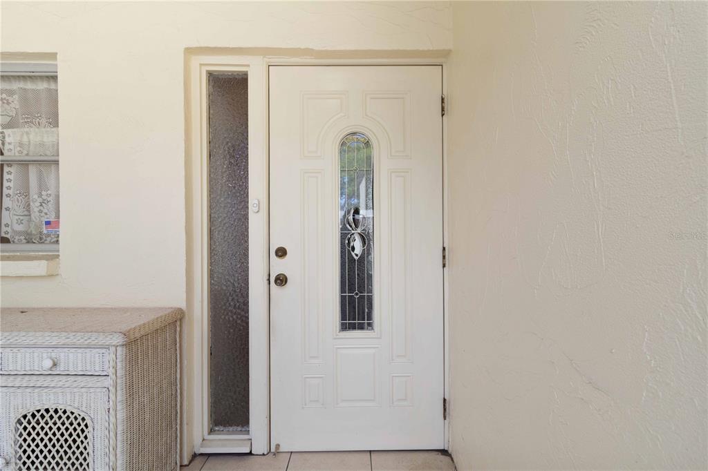 A white front door with a decorative glass insert sits next to a side window — 6215 GREEN VIEW CIRCLE UNIT 74, SARASOTA, FL