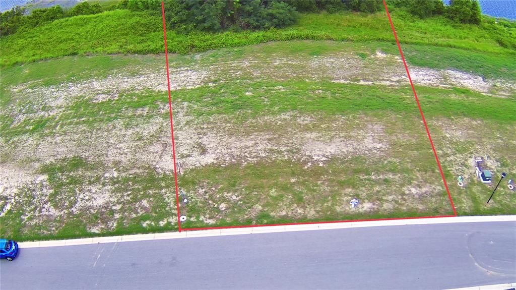 An aerial view shows a vacant, grassy residential lot outlined in red next to a road — 4383 JULIANA LAKE DRIVE, AUBURNDALE, FL