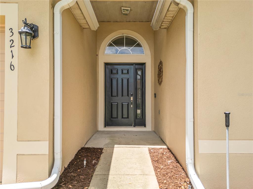 A front entryway features a dark door with a sidelight and an arched transom window — 3216 PARK BRANCH AVENUE, CLERMONT, FL
