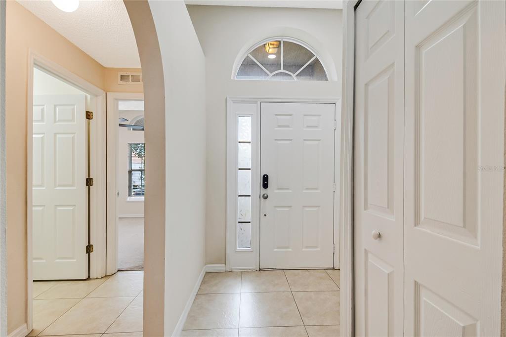 An entryway features a white front door with a sidelight, arched transom, and tile flooring — 3216 PARK BRANCH AVENUE, CLERMONT, FL
