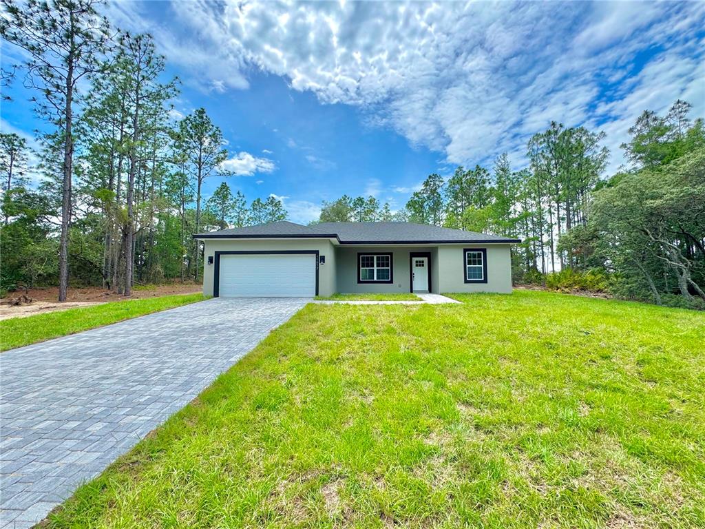 A single-story house with a paved driveway and a green lawn under a blue sky — 11032 N TRIGGER TERRACE, CITRUS SPRINGS, FL
