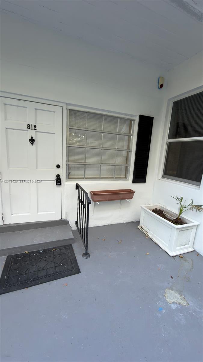 A white front door with the number 812 sits beside a window and a porch — 808 84th St # 812, Miami Beach FL 33141, MIAMI BEACH, FL