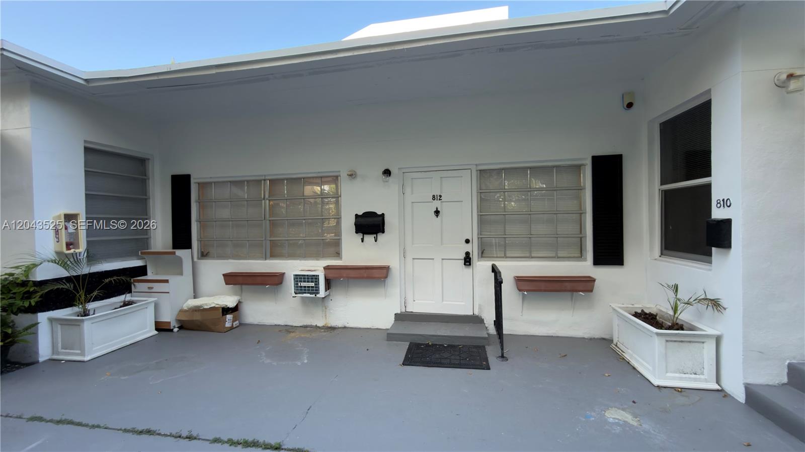The exterior of a white building features a front door, windows, and two planter boxes — 808 84th St # 812, Miami Beach FL 33141, MIAMI BEACH, FL