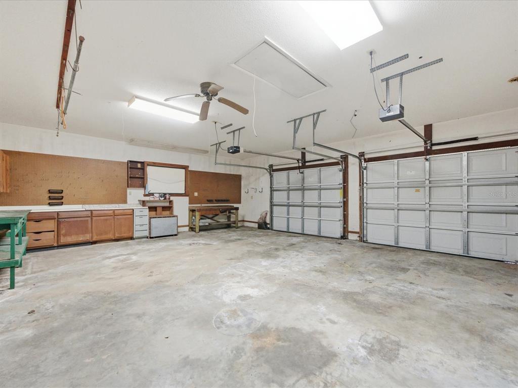 A spacious garage with a concrete floor, workbench, cabinetry, and two overhead garage doors — 8979 W WHITE DOGWOOD DRIVE, HOMOSASSA, FL