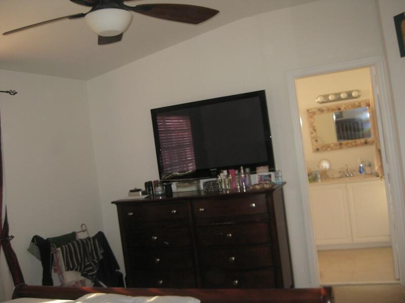 A bedroom features a dark wood dresser, a wall-mounted television, and an adjacent bathroom doorway — 4070 NW 91st Terrace, Sunrise FL 33351, SUNRISE, FL