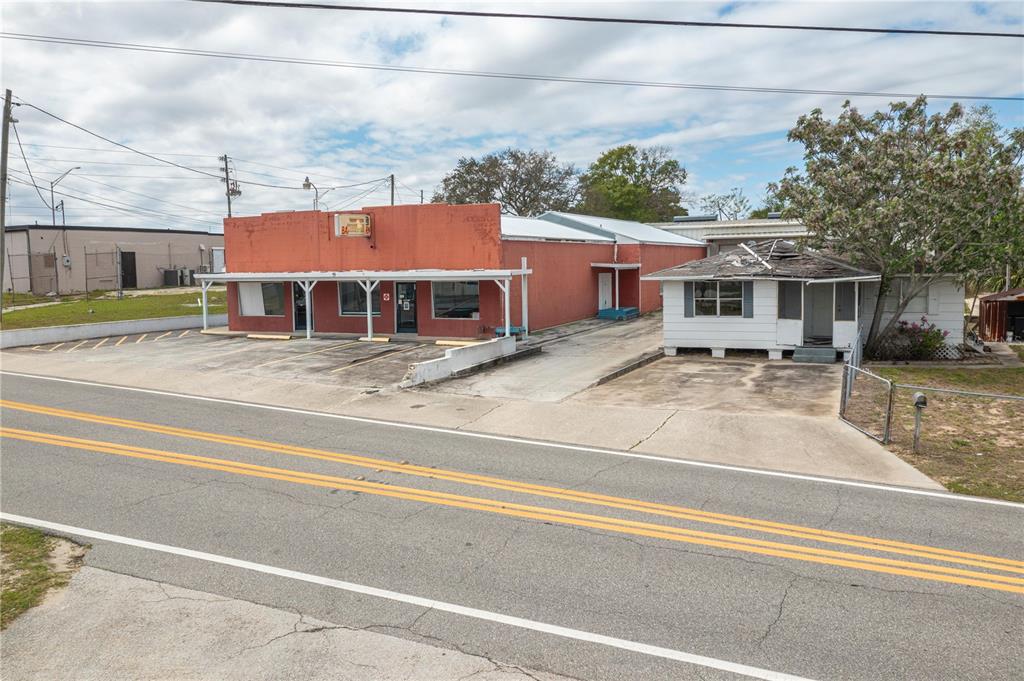 An exterior view of a red commercial building next to a small white house — 19 EVERGREEN DRIVE, LAKE WALES, FL