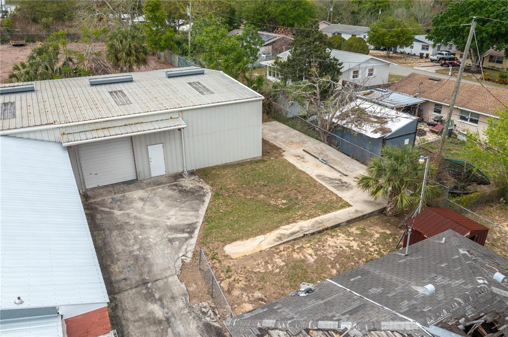 An aerial view shows a metal warehouse building, a concrete driveway, and adjacent residential properties — 19 EVERGREEN DRIVE, LAKE WALES, FL