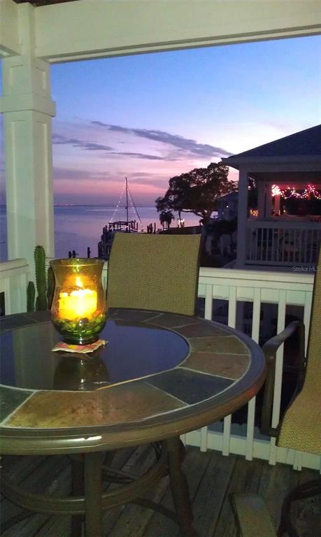 A round tile-topped table with a lit candle sits on a deck overlooking the water — 5184 BEACH DRIVE SE UNIT D, ST PETERSBURG, FL